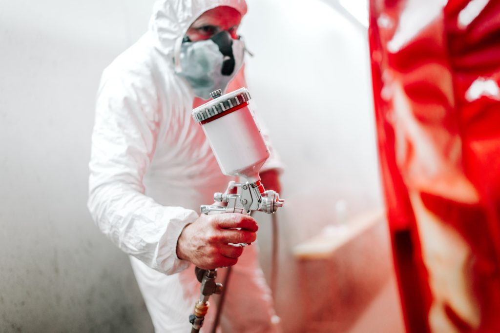 car painting details in automotive manufacturing industry. worker painting a car in special booth